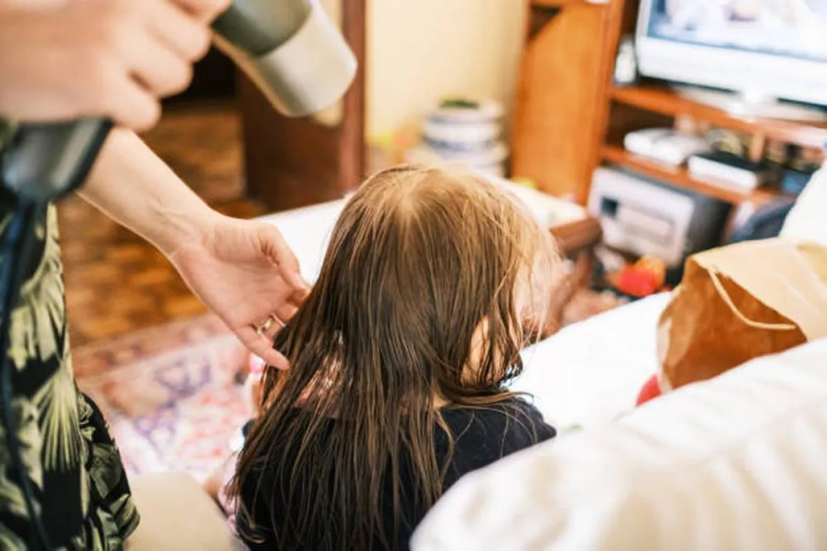 صورة لأم تجفف شعر طفلتها بالمجفف الكهربائي