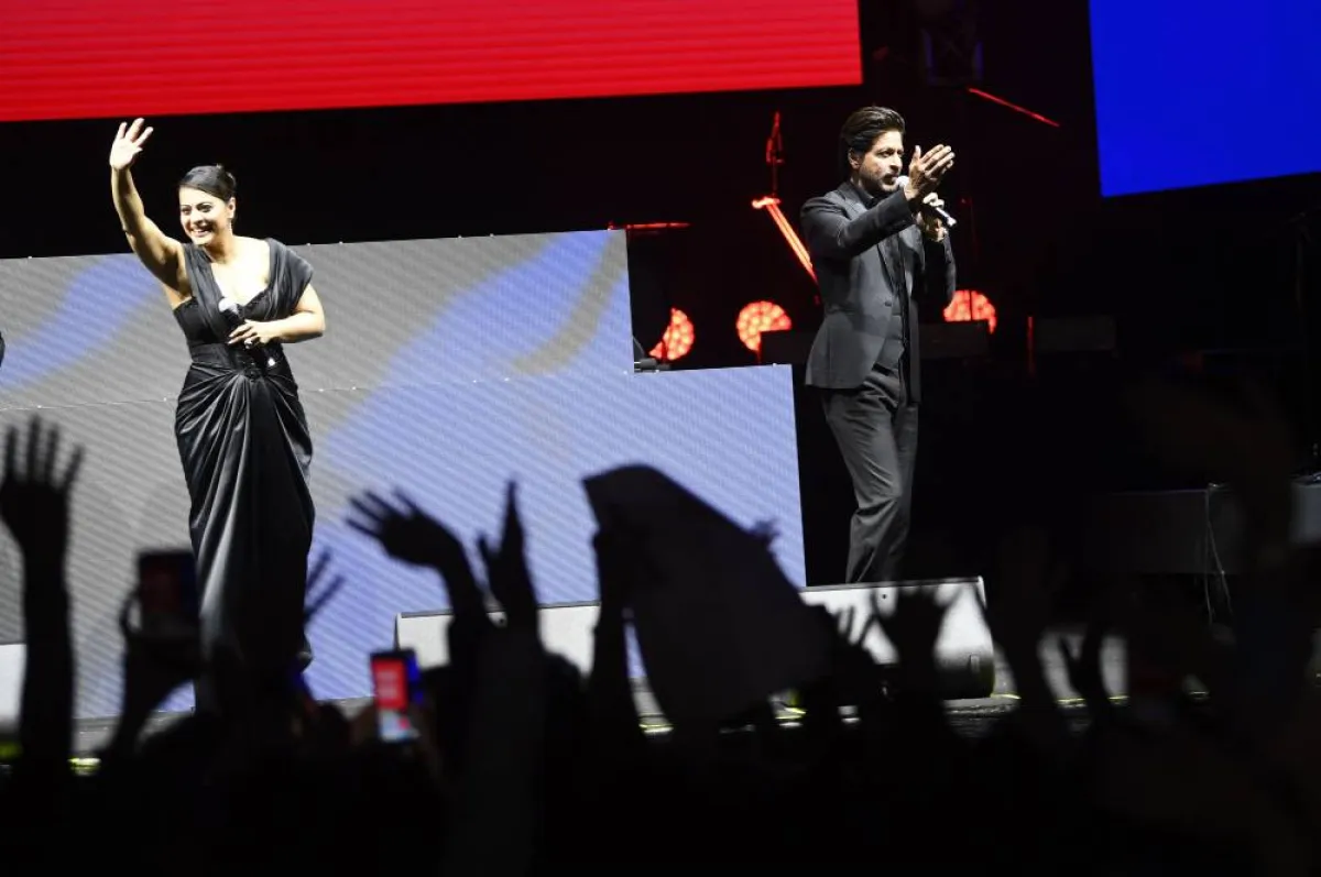 Indian actor, film producer, and television personality Shah Rukh Khan talks to his fans as Indian actress Kajol Devgan commonly known as Kajol waves with her hand at the corniche during the opening of the Red Sea International Film Festival, in Jeddah, Saudi Arabia, on December 1, 2022. AMER HILABI / Red Sea Film Festival
