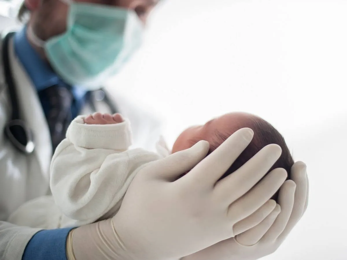 صورة لطبيب يحمل طفلاً حديث الولادة