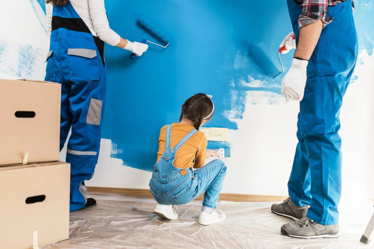 صورة طفلة تساعد في طلاء الجدار