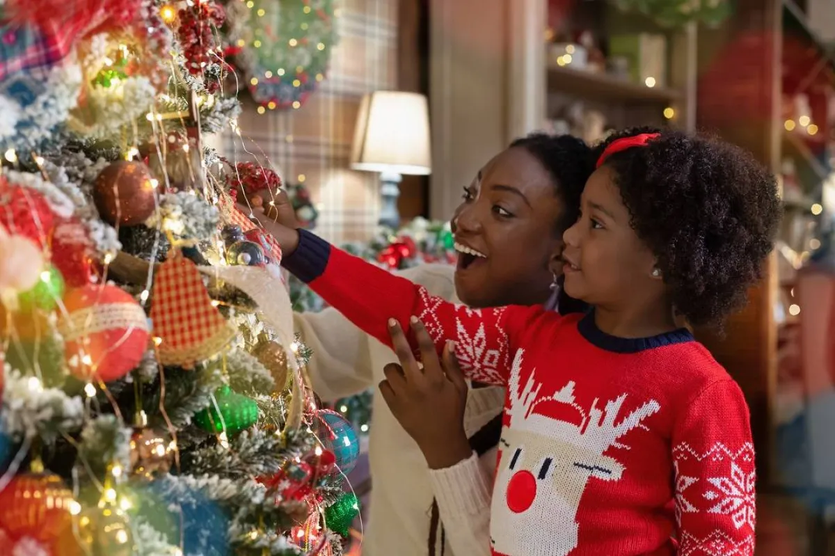 صورة لطفلة وأمها يزينان شجرة رأس السنة