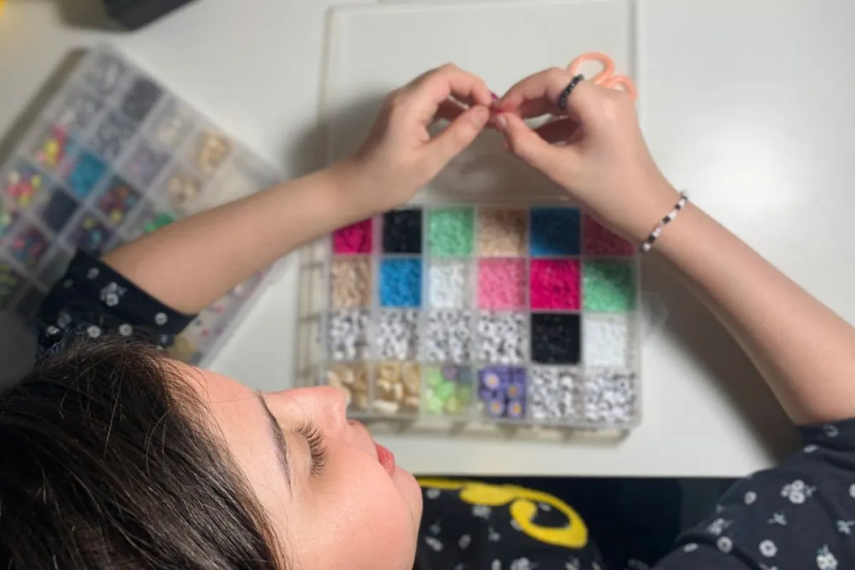 تظهر الصورة الطفلة وهي تصنع الخرز