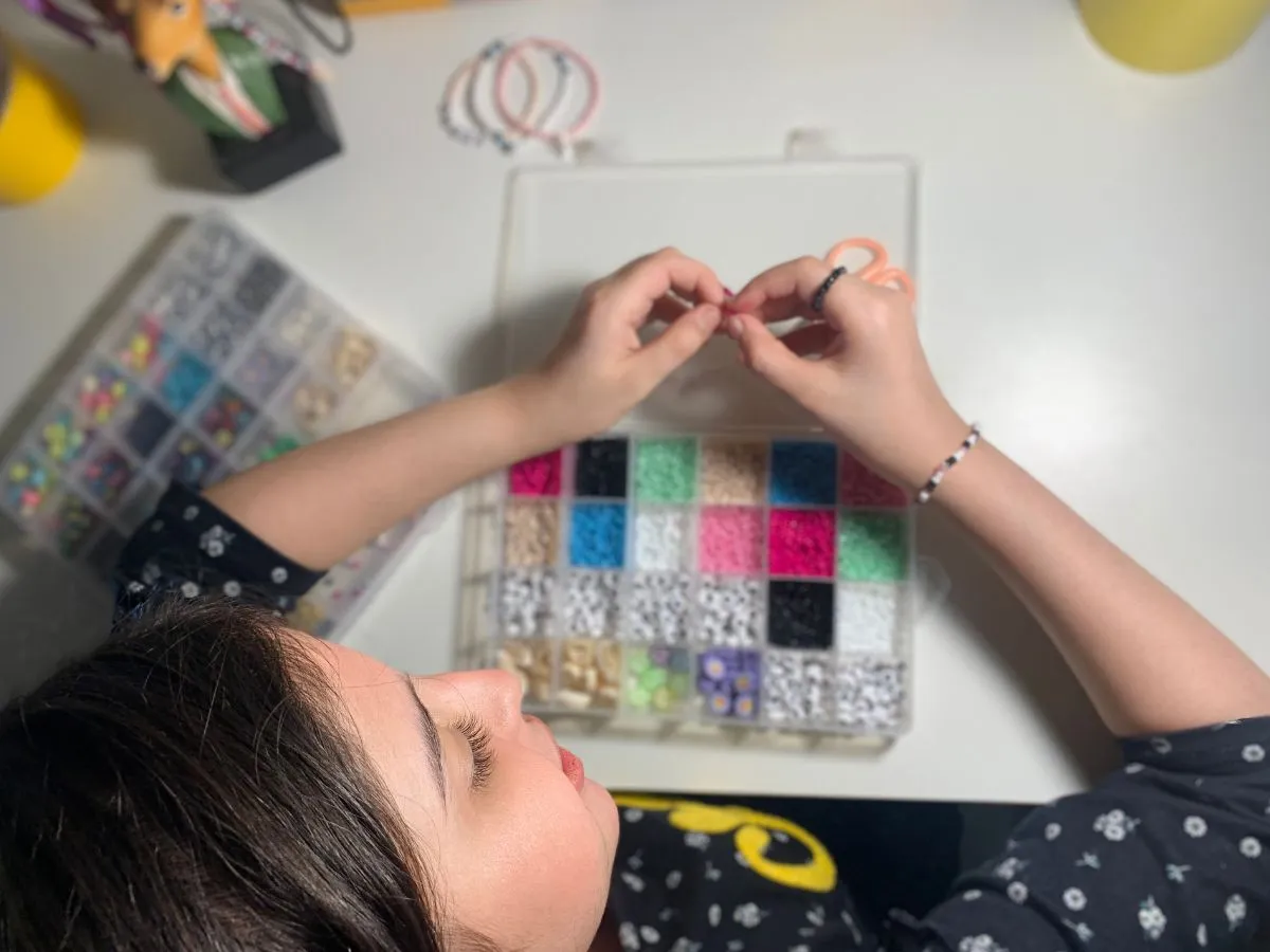 تظهر الصورة الطفلة وهي تصنع الخرز