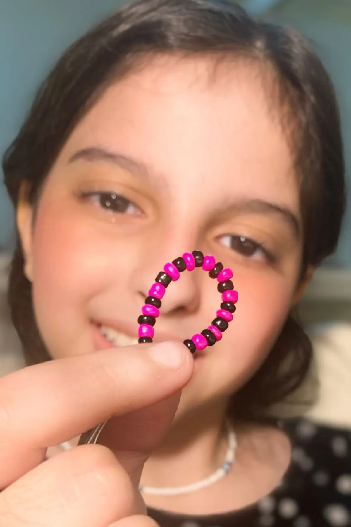 تظهر الصورة الطفلة وهي تصنع الخرز