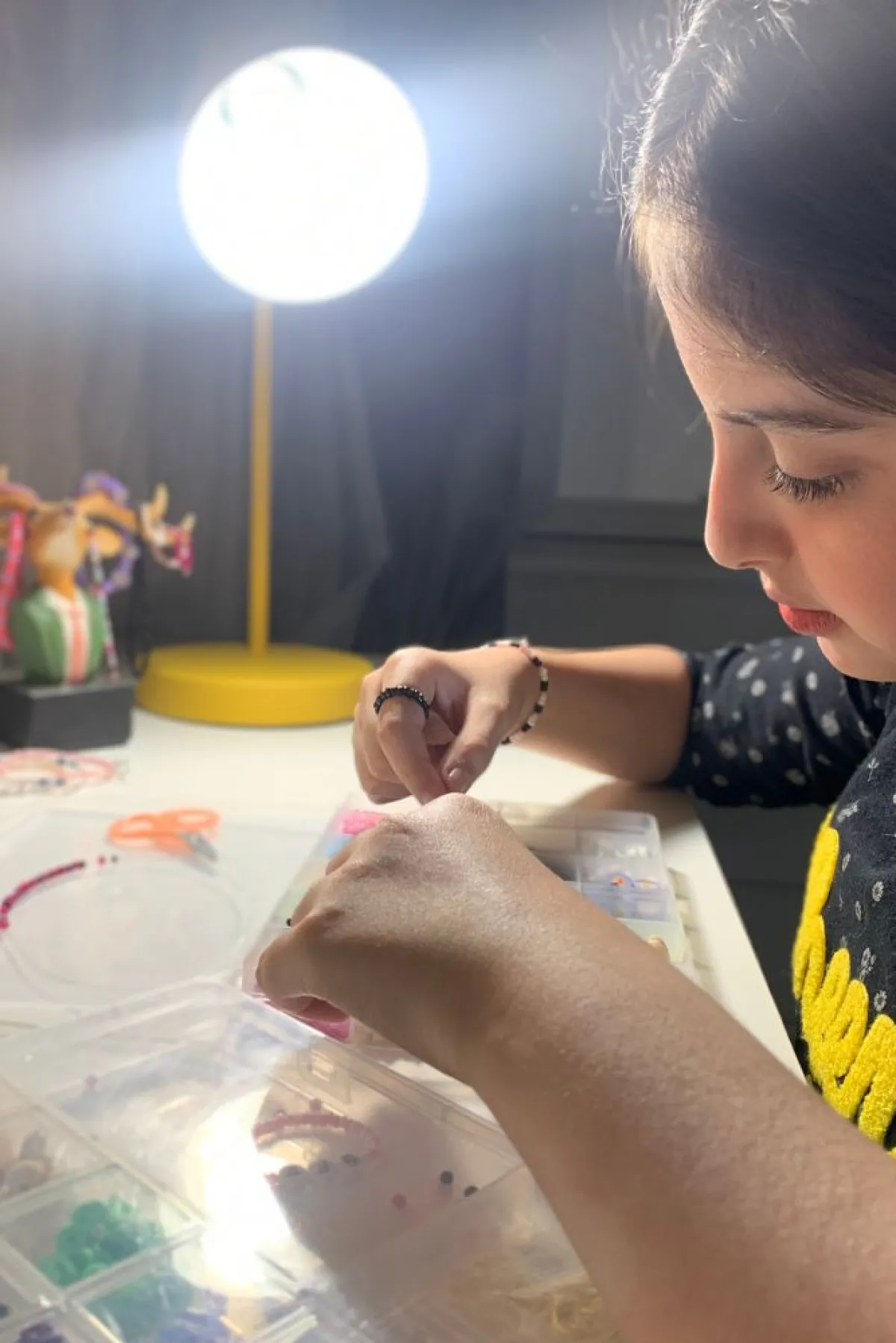 تظهر الصورة الطفلة وهي تصنع الخرز