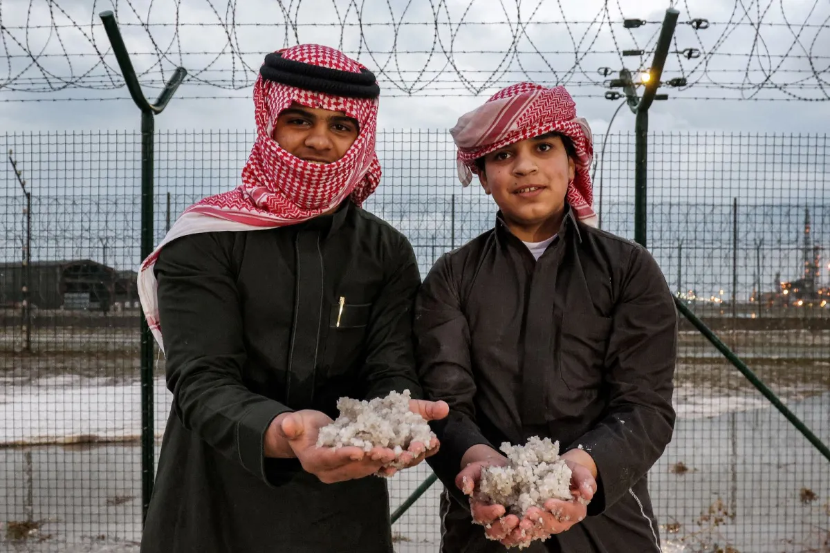 شبان يلتقطون حبات البردعلى جانب الطريق 