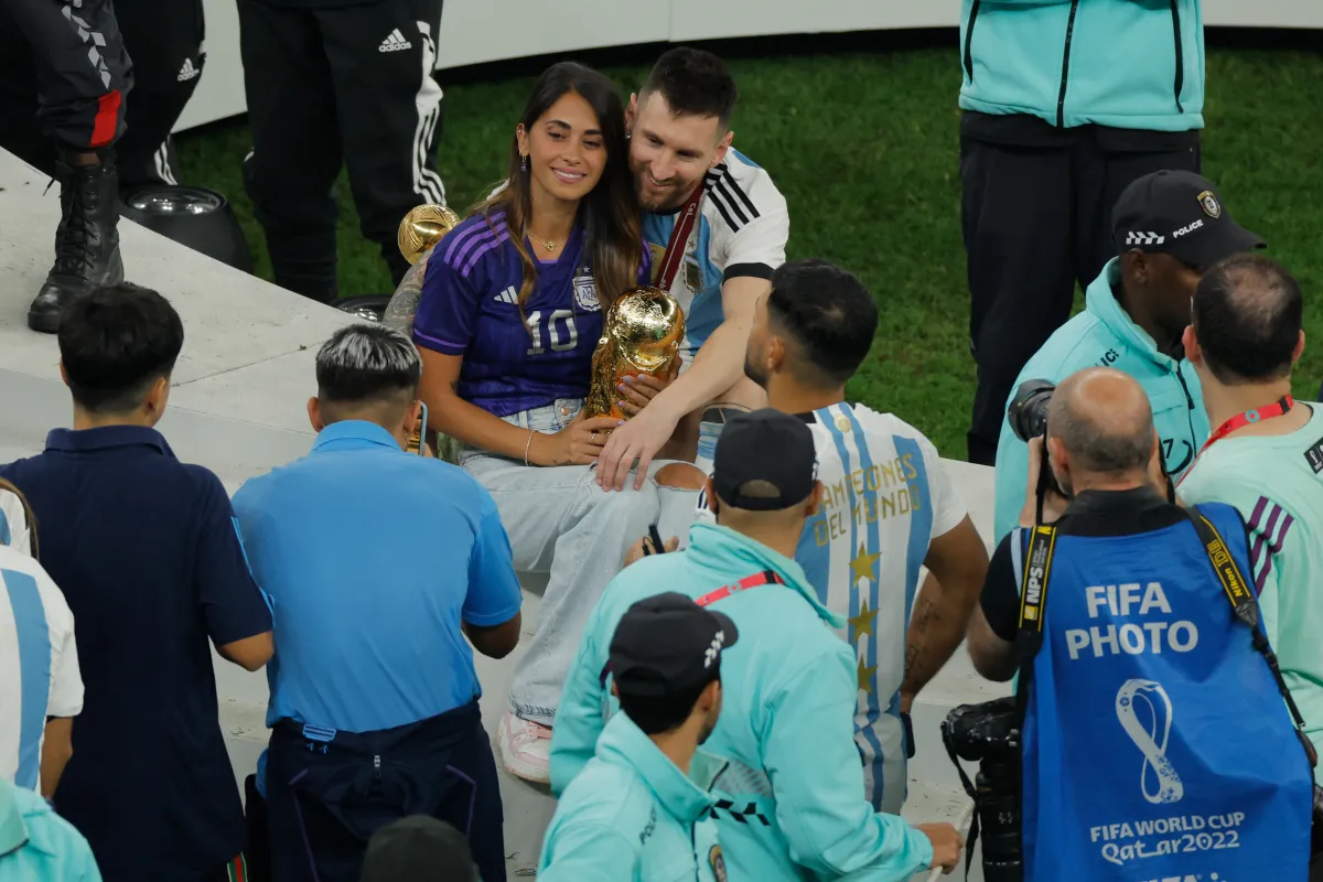  Lionel Messi and his wife Antonela Roccuzzo pose while holding the World Cup Trophy at the end of the Qatar 2022 World Cup final football match between Argentina and France at Lusail Stadium in Lusail, north of Doha on December 18, 2022. Odd ANDERSEN / AFP