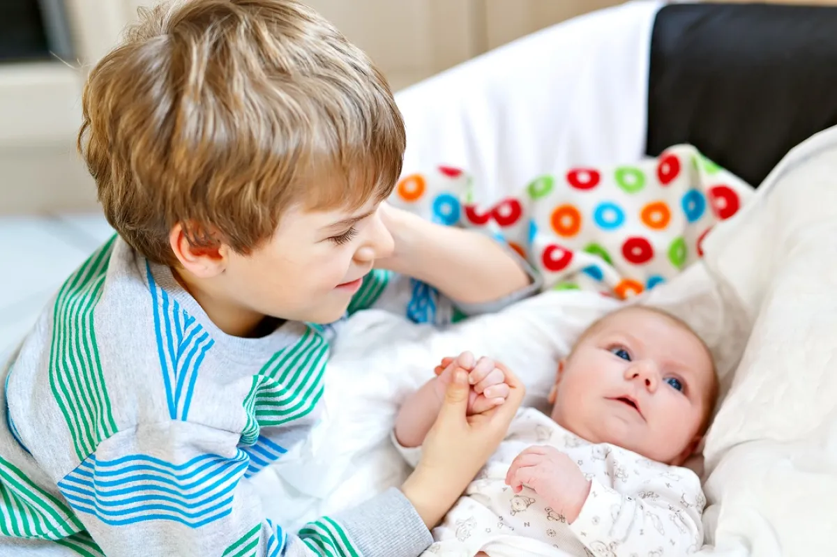 صورة للطفل يلعب مع المولود