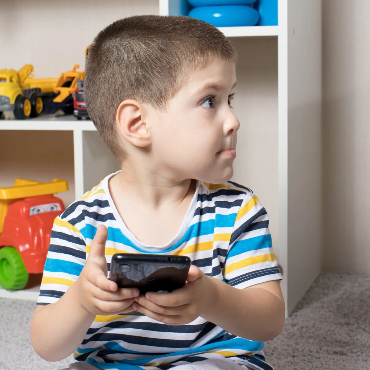 صورة لطفل صغير والشاشة بين يديه