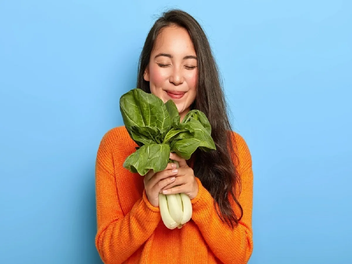 صورة لامرأة تحمل خضروات ورقية خضراء