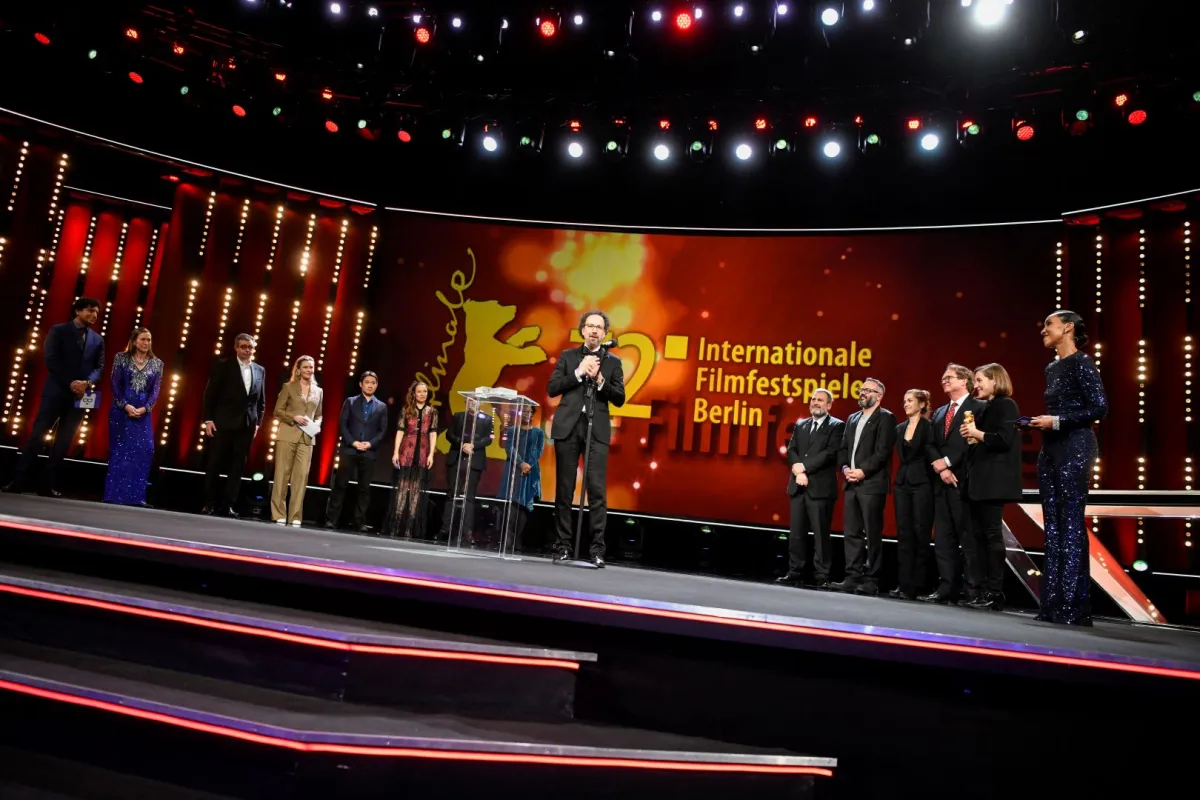 Berlinale Artistic Director Carlo Chatrian (C) speaks on stage as the members of the International Jury stand at (L) and the team of the film "Alcarras", winner of the Golden Bear for Best Film with Spanish director and screenwriter Carla Simon (2ndR), producer Maria Zamora (4thR) and German TV host Hadnet Tesfai listen during the awards ceremony of the 72nd Berlinale Film Festival in Berlin on February 16, 2022. Stefanie LOOS / AFP