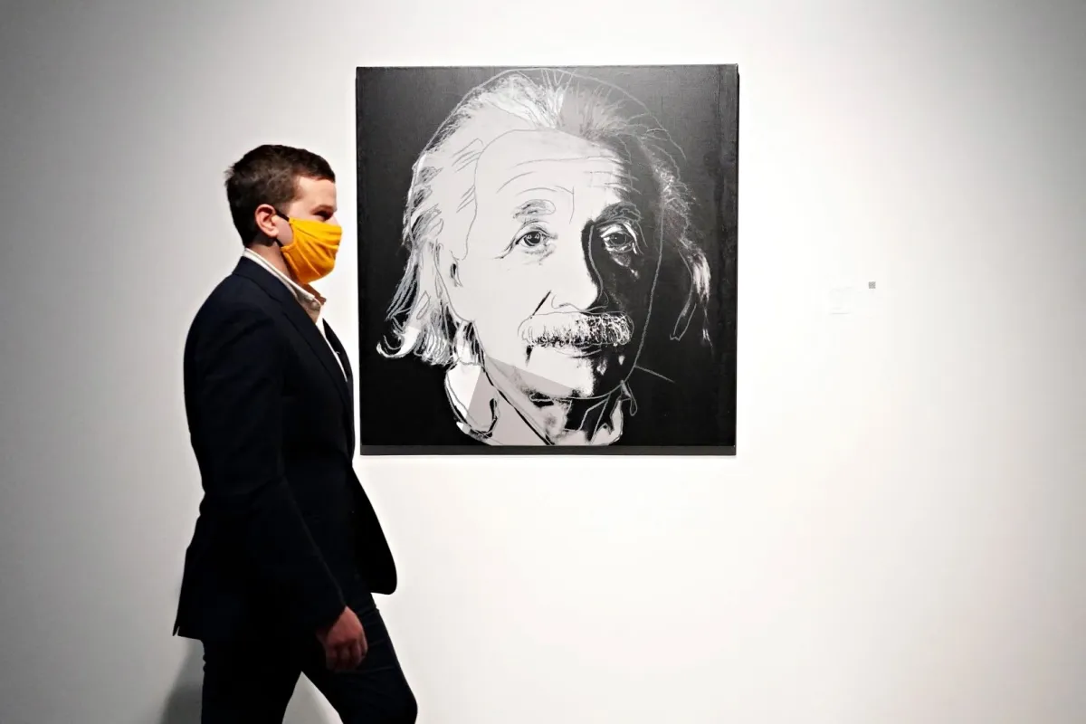 A person wearing a protective mask walks by Andy Warhol's Albert Einstein (from Ten Portraits of Jews of the Twentieth Century) during a press preview of the upcoming Contemporary Art Evening Auction at Sotheby's on October 23, 2020 in New York City. Cindy Ord/Getty Images/AFP Cindy Ord / GETTY IMAGES NORTH AMERICA / Getty Images via AFP