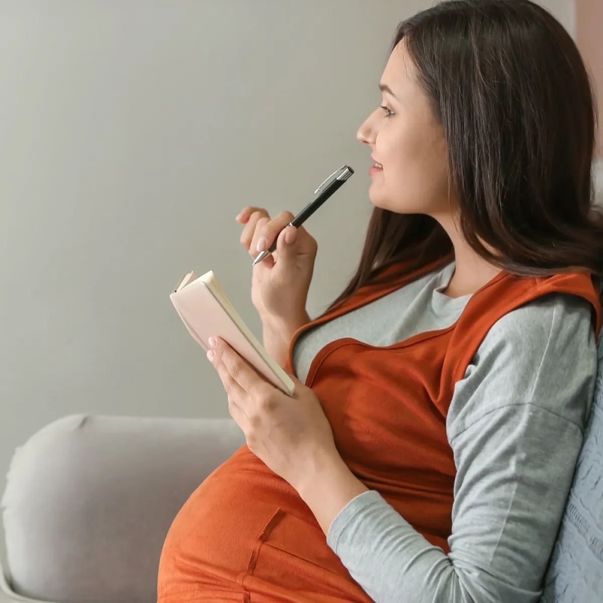 صورة لحامل تكتب وتخطط لأستقبال المولود