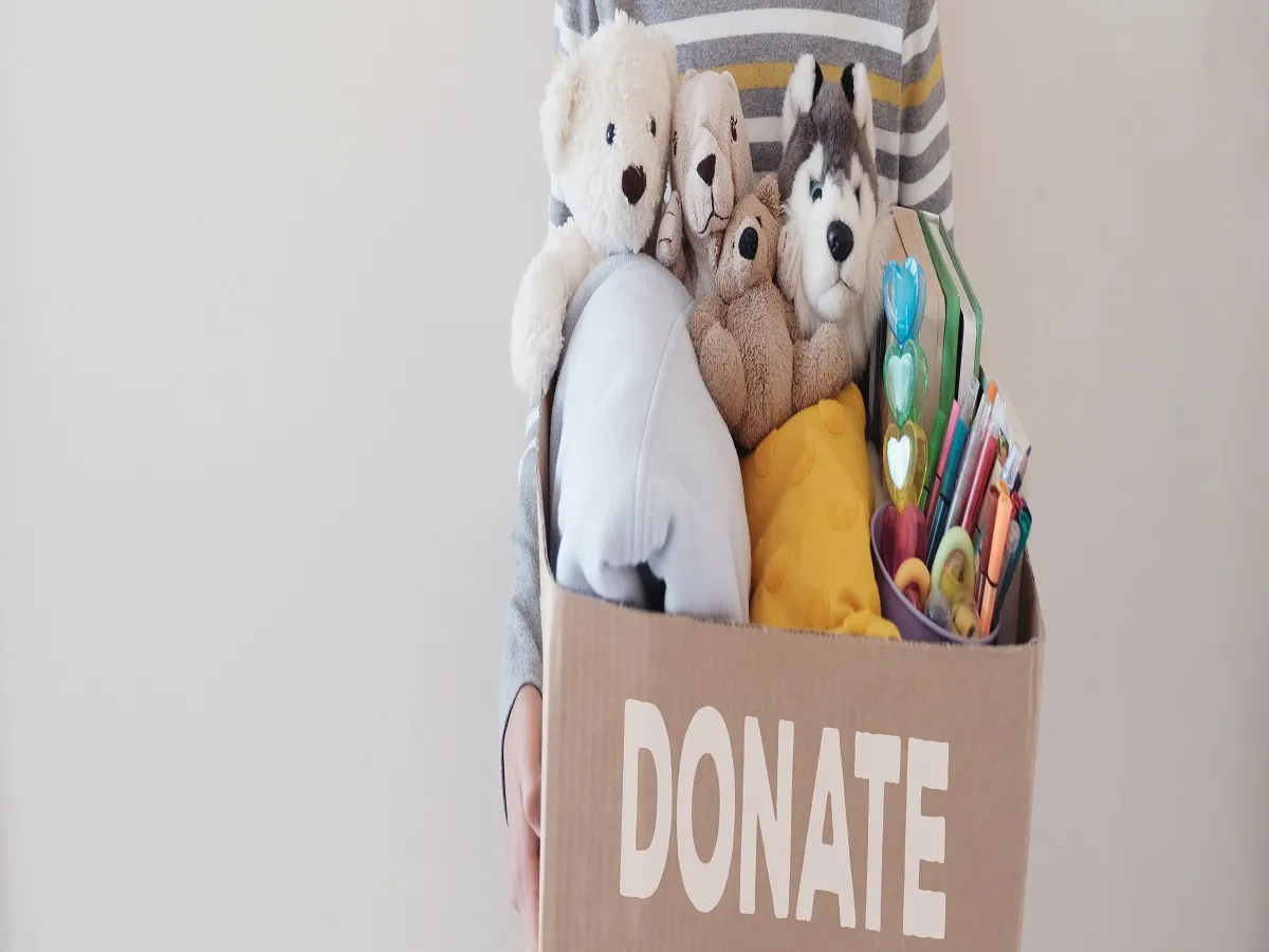 صورة لطفل يحمل صندوق تبرعات مليئاً بالألعاب