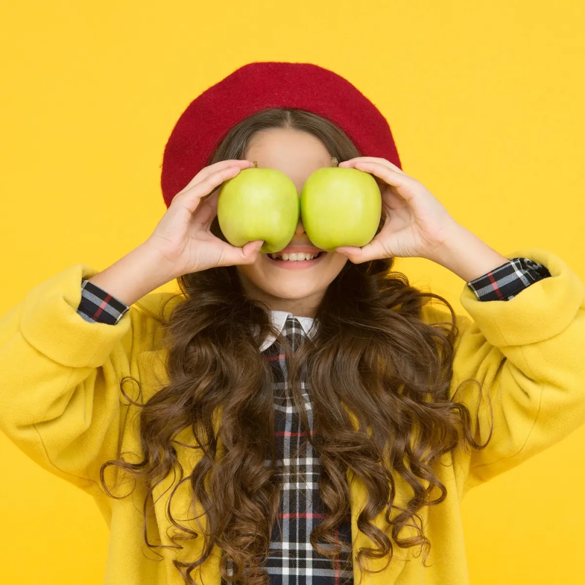 صورة لطفلة تحمل تفاحتين