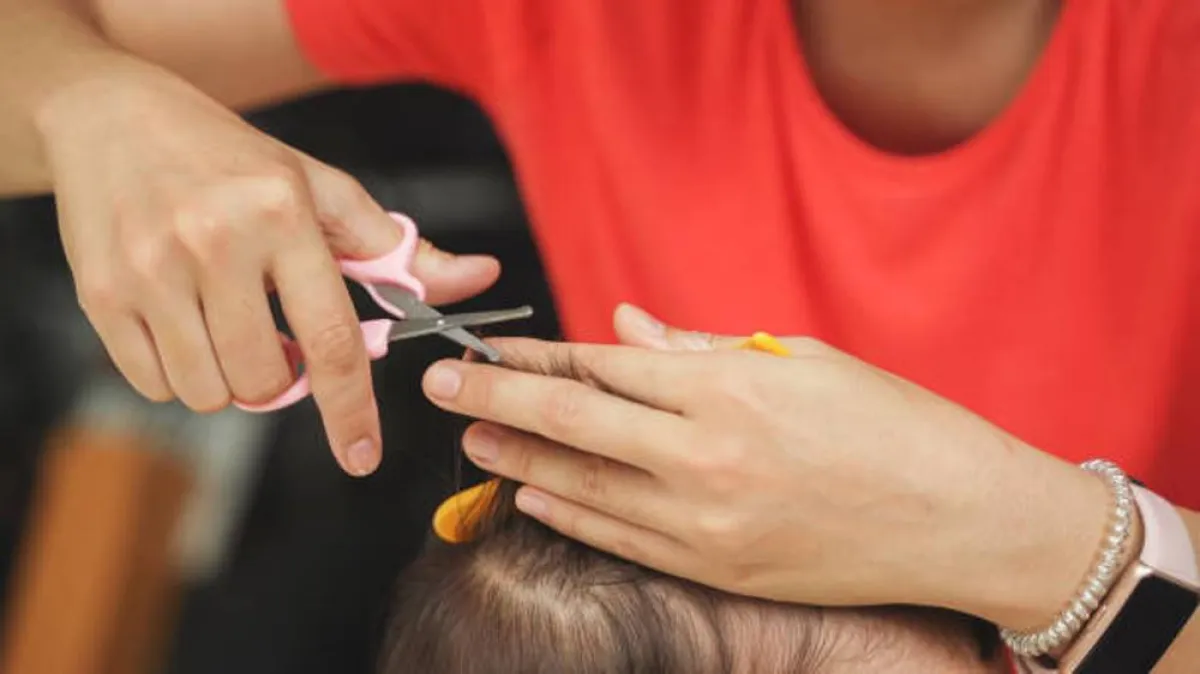 صورة لأم تقوم بقص أطراف شعر طفلها