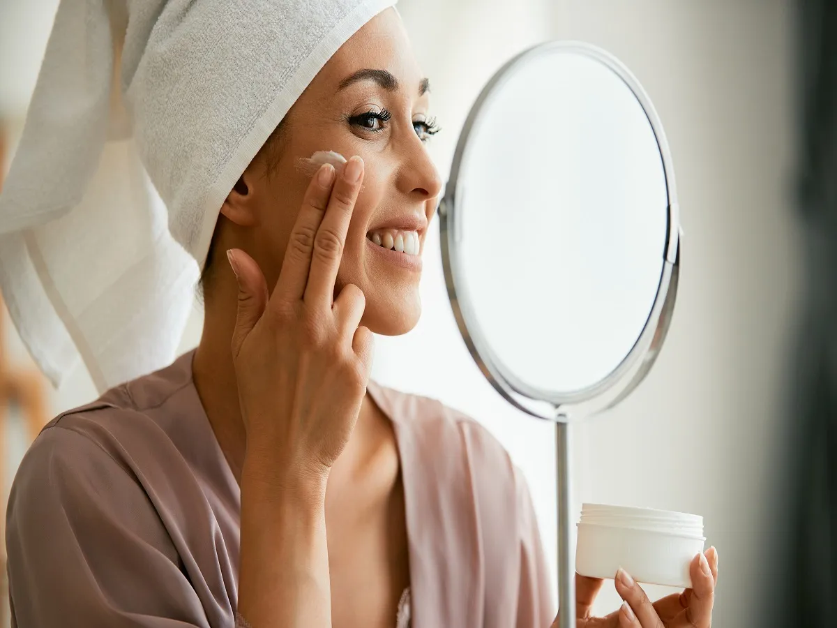 صورة لامرأة تضع كريم تجميلي على وجهها