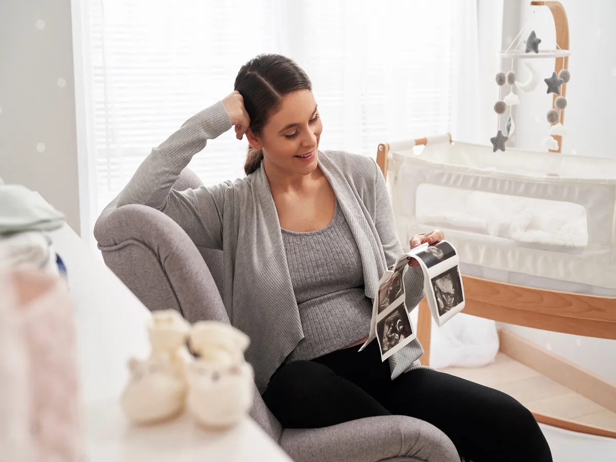 صورة لامرأة حامل تحمل صورة موجات فوق صوتية