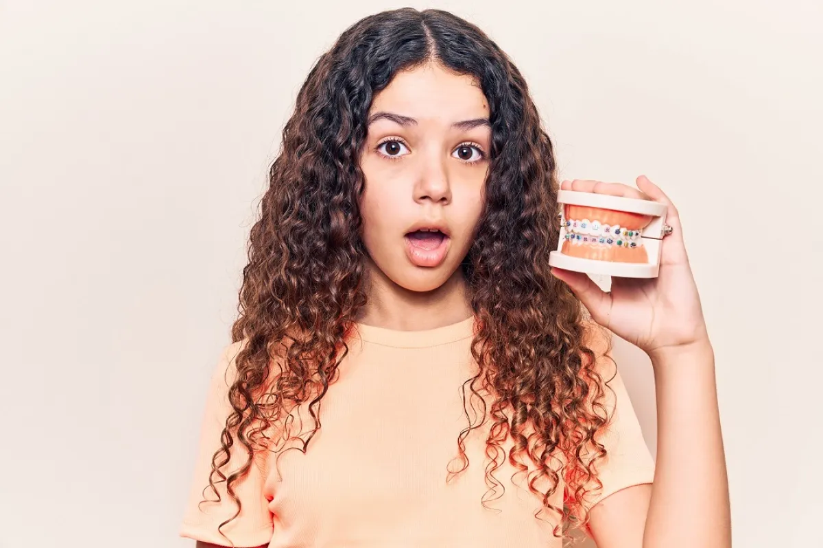 صورة لطفلة تمسك بتقويم الأسنان