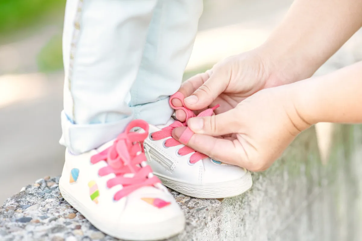 صورة لأم تربط حذاء طفلتها
