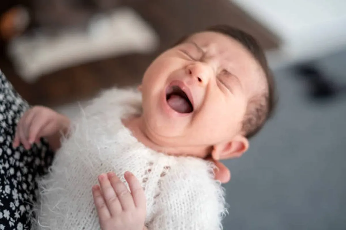 صورة لرضيع يبكي بين يدي أمه