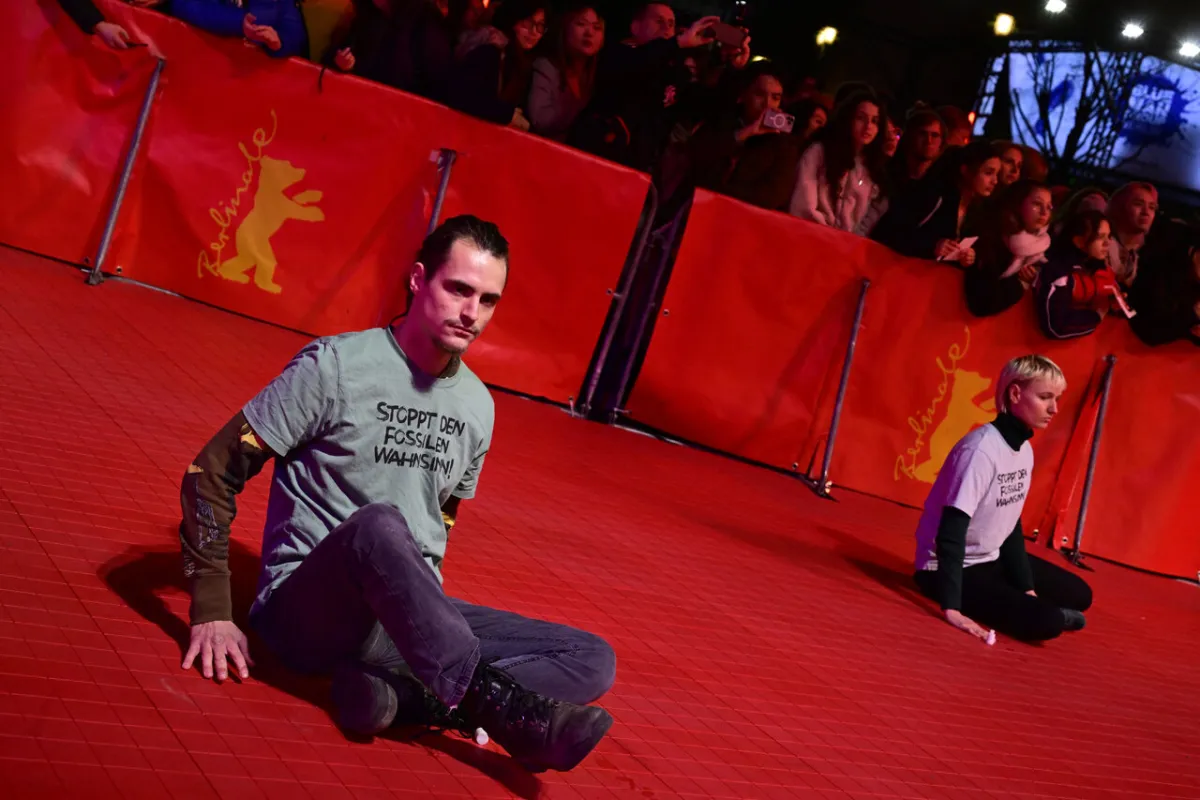 ActivistS of the environmental group "Last Generation" (Letzte Generation) are glued on the ground near the red carpet with a T-shirt reading "Stop the fossil fuel madness" at the premiere of the film "She Came To Me" presented in the Berlinale Special Gala section, that opens the Berlinale, Europe's first major film festival of the year, on February 16, 2023 in Berlin. John MACDOUGALL / AFP