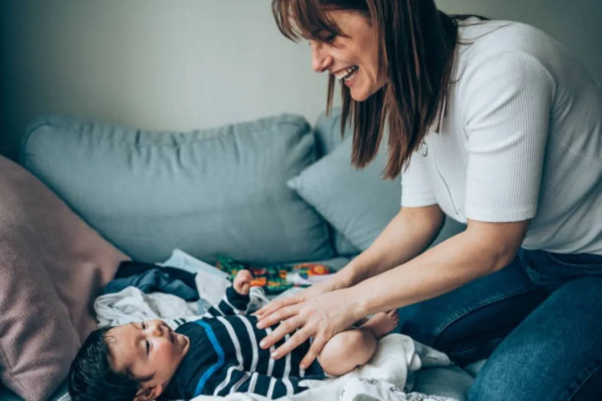 صورة لأم تقوم بتغيير حفاض طفلها