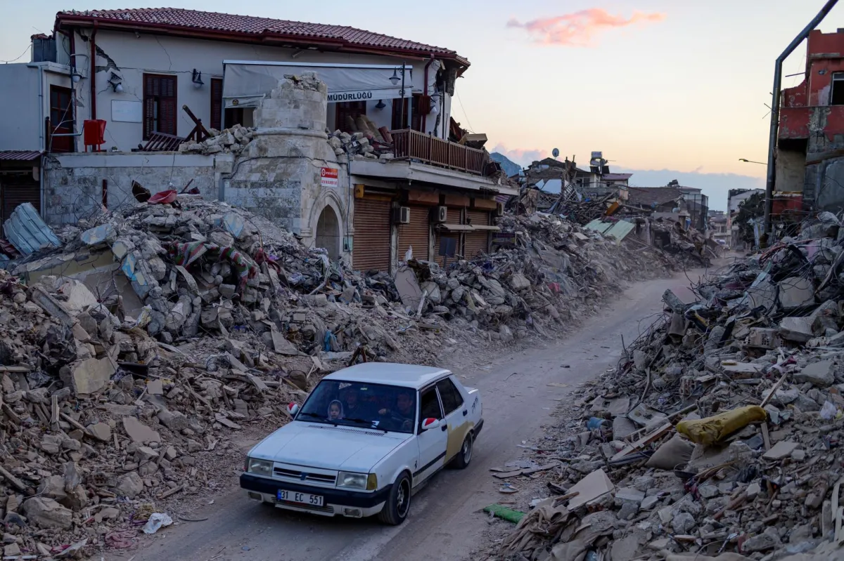 A car drives past collapsed buildings in Antakya, southern Turkey on February 20, 2023. Yasin AKGUL / AF