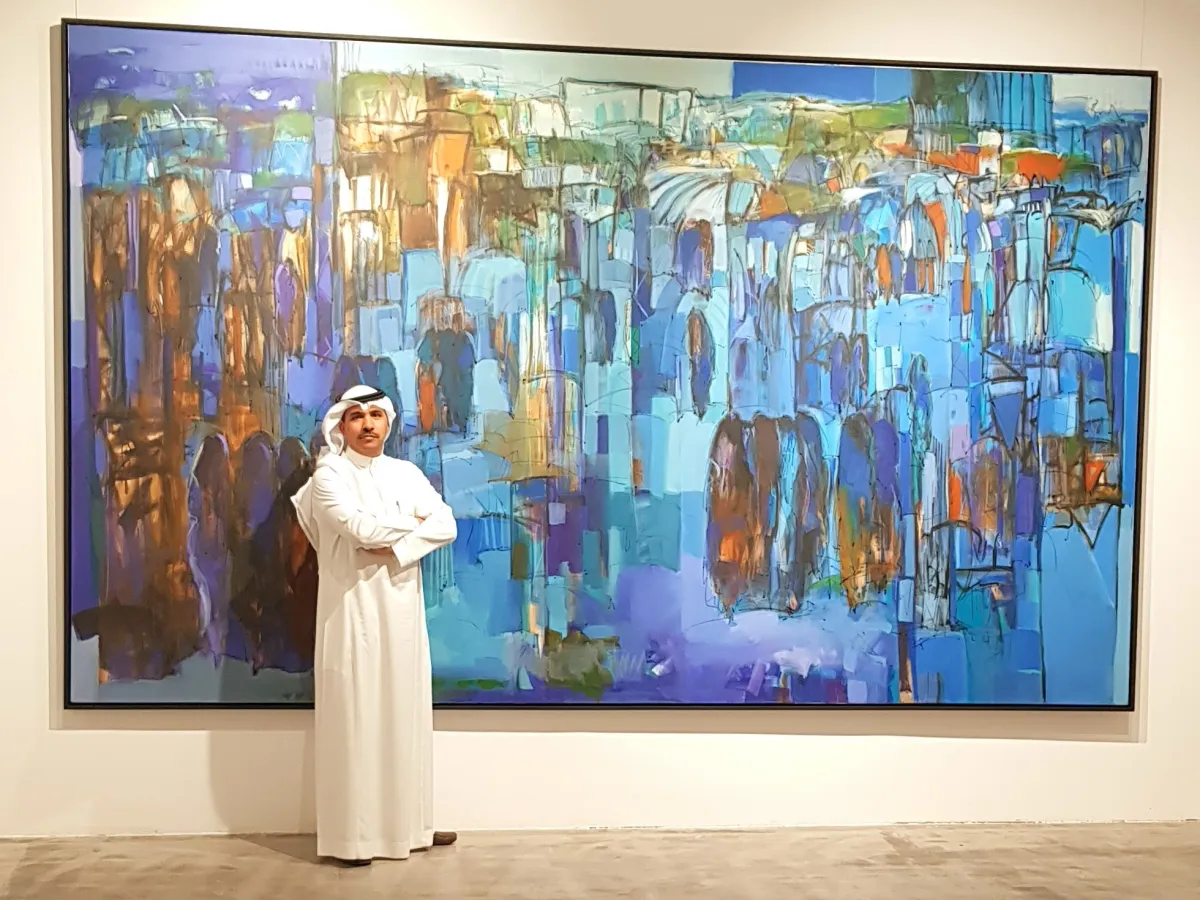 الفنان عبدالله الأحمري بجانب لوحته المعروضة في صالة آرت فيجن