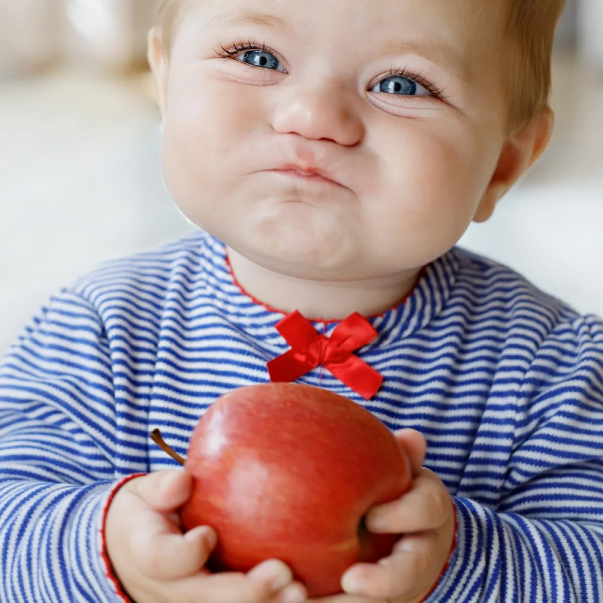 صورة لطفل يمسك بالتفاحة بين يديه