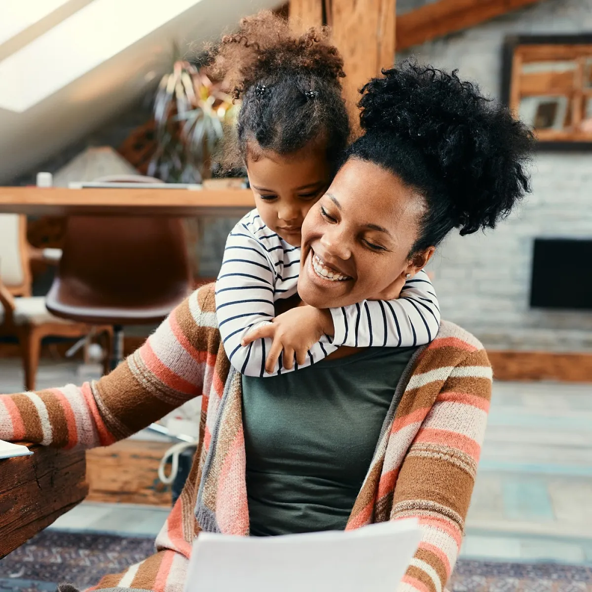 صورة لأم تعمل وطفلتها تحتضنها