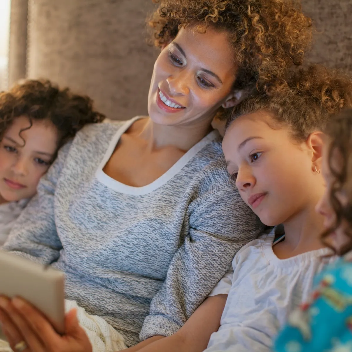 صورة لأم تقرأ لطفلتيها ماقالوه عن الأم