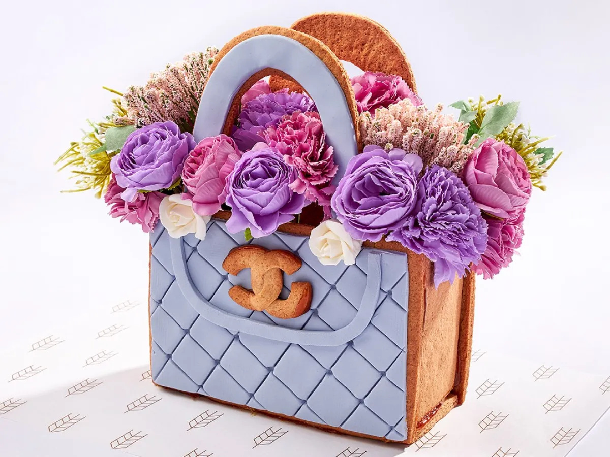 قالب حلوى على شكل حقيبة باللون الأزرق ومزينة بالزهور الطبيعية