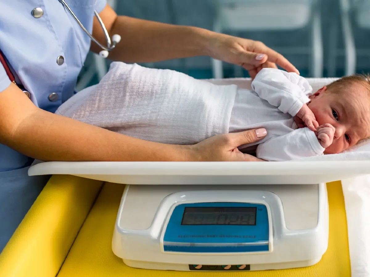 صورة لطبيبة تقوم بوزن طفل رضيع