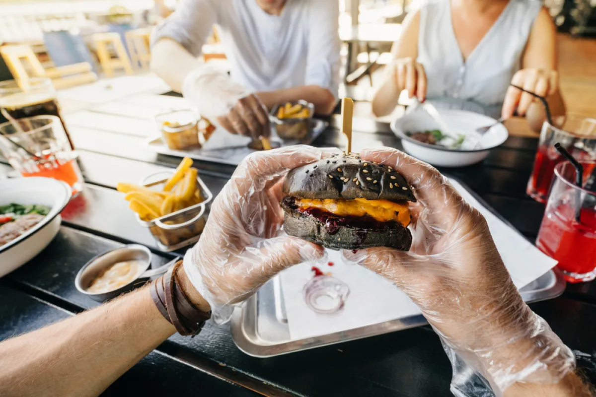 اليدان تغلفان بقفازي الأكل عن تناول البرجر