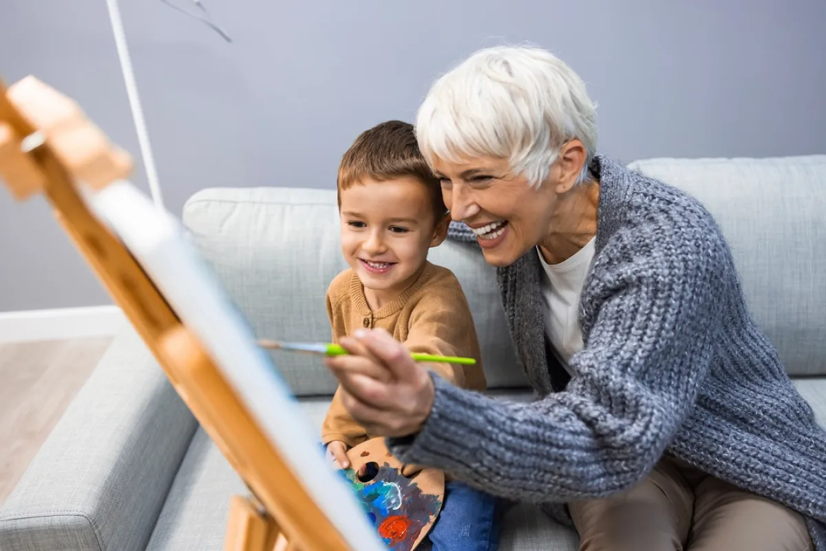 صورة للجدة تعلم حفيدها الرسم بالألوان