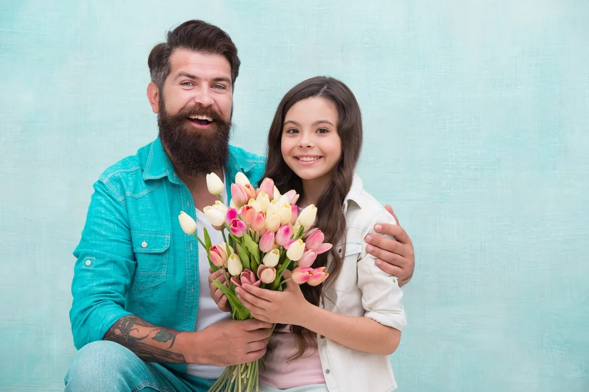 صورة لطفلة تقدم الورود لأبيها في يومه