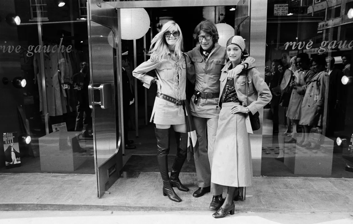   إيف سان لوران يتوسط ملهمتيه من اليمين لولو دو لا فاليز ومن اليسار بيتي كاترو،في افتتاح البوتيك الخاصة به في لندن، عام 1969،Yves Saint Laurent, designer with muses Louise de La Falaise, aka Loulou (right) and Betty Catroux (left), 10th September 1969. (مصدر الصورة: Dorean Spooner/Mirrorpix/Getty Images)
