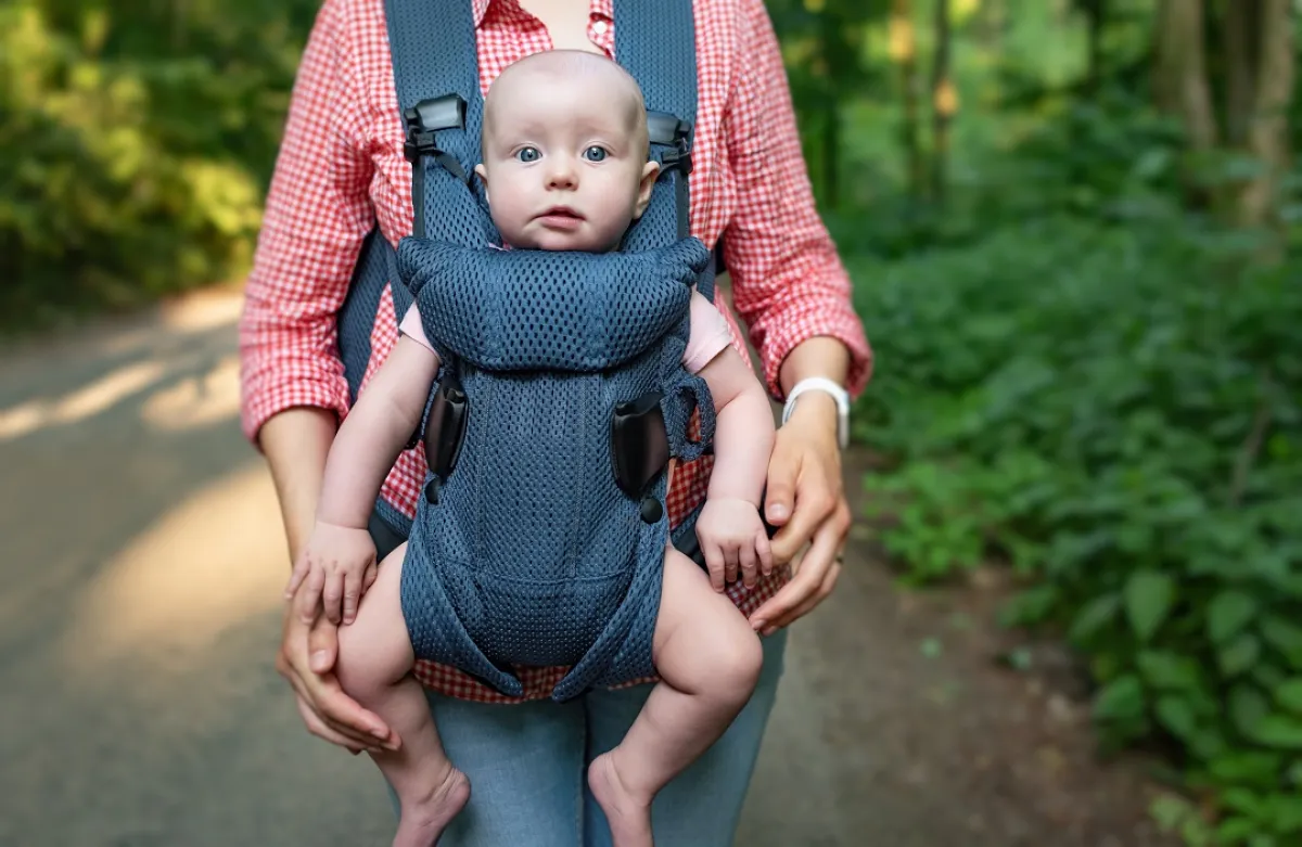 صورة لأم تحمل طفلها بشيالة الاطفال