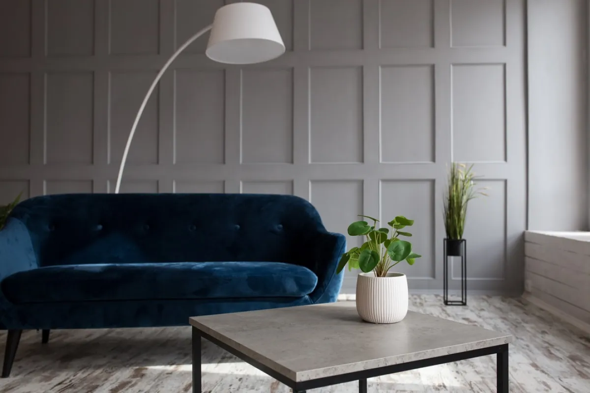 أريكة مكسوة بنسيج مخملي أزرق داكن، في غرفة الجلوس الضيقة