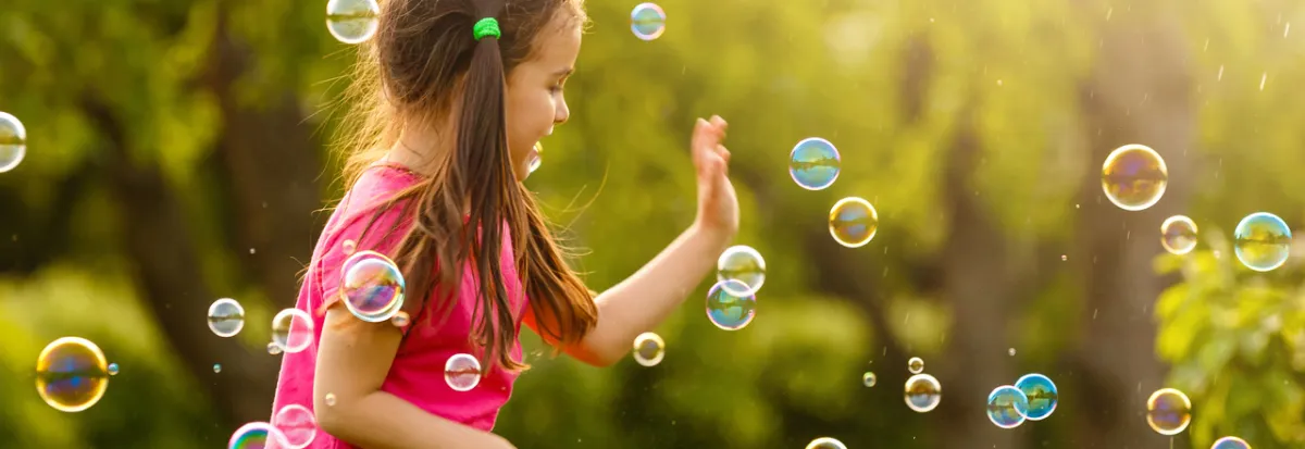 صورة طفلة تلعب بفقاعات الصابون
