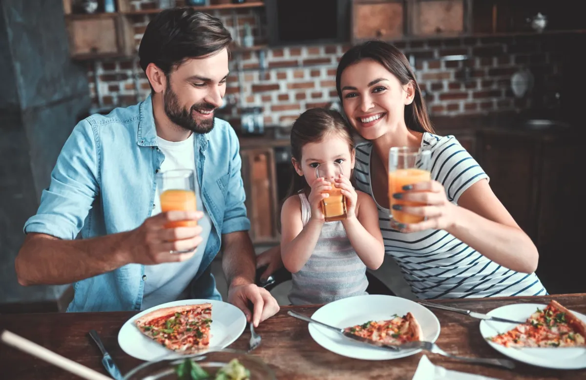 صورة لعائلة تتناول طعامها في المنزل بكل سعادة