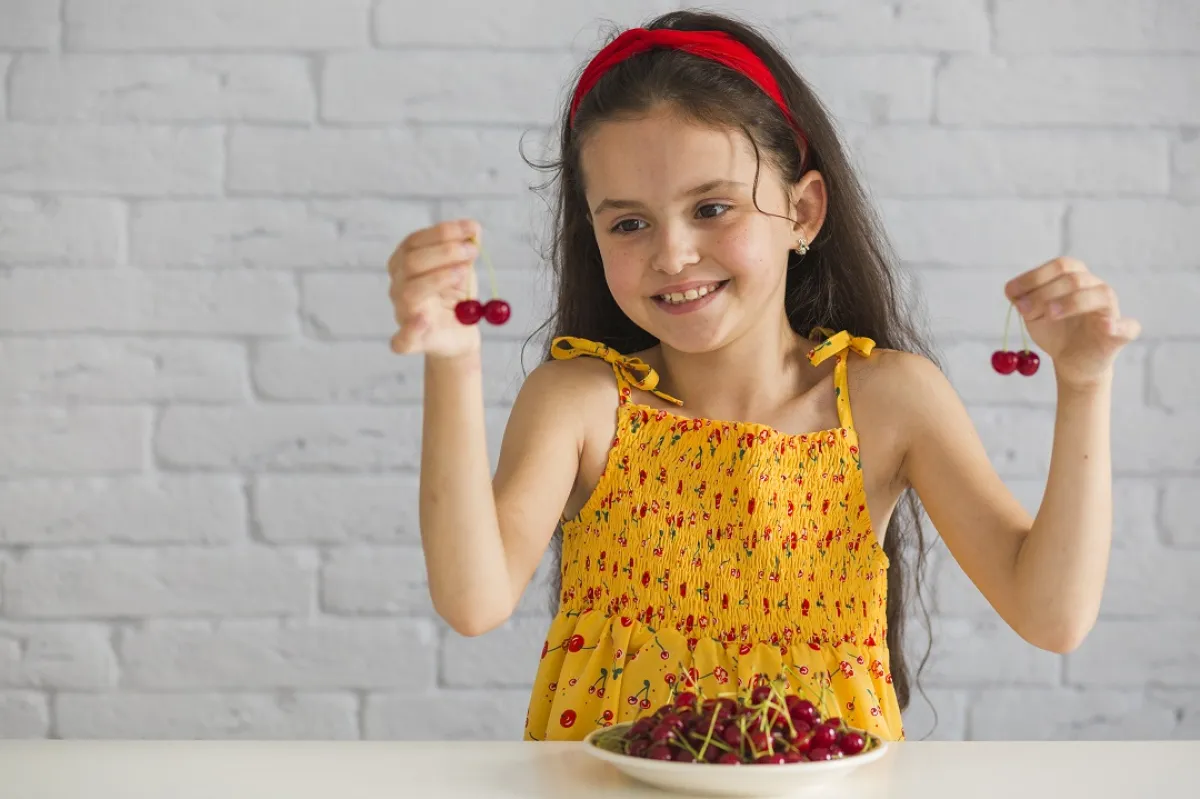 صورة لطفلة تحمل حبات من الكرز
