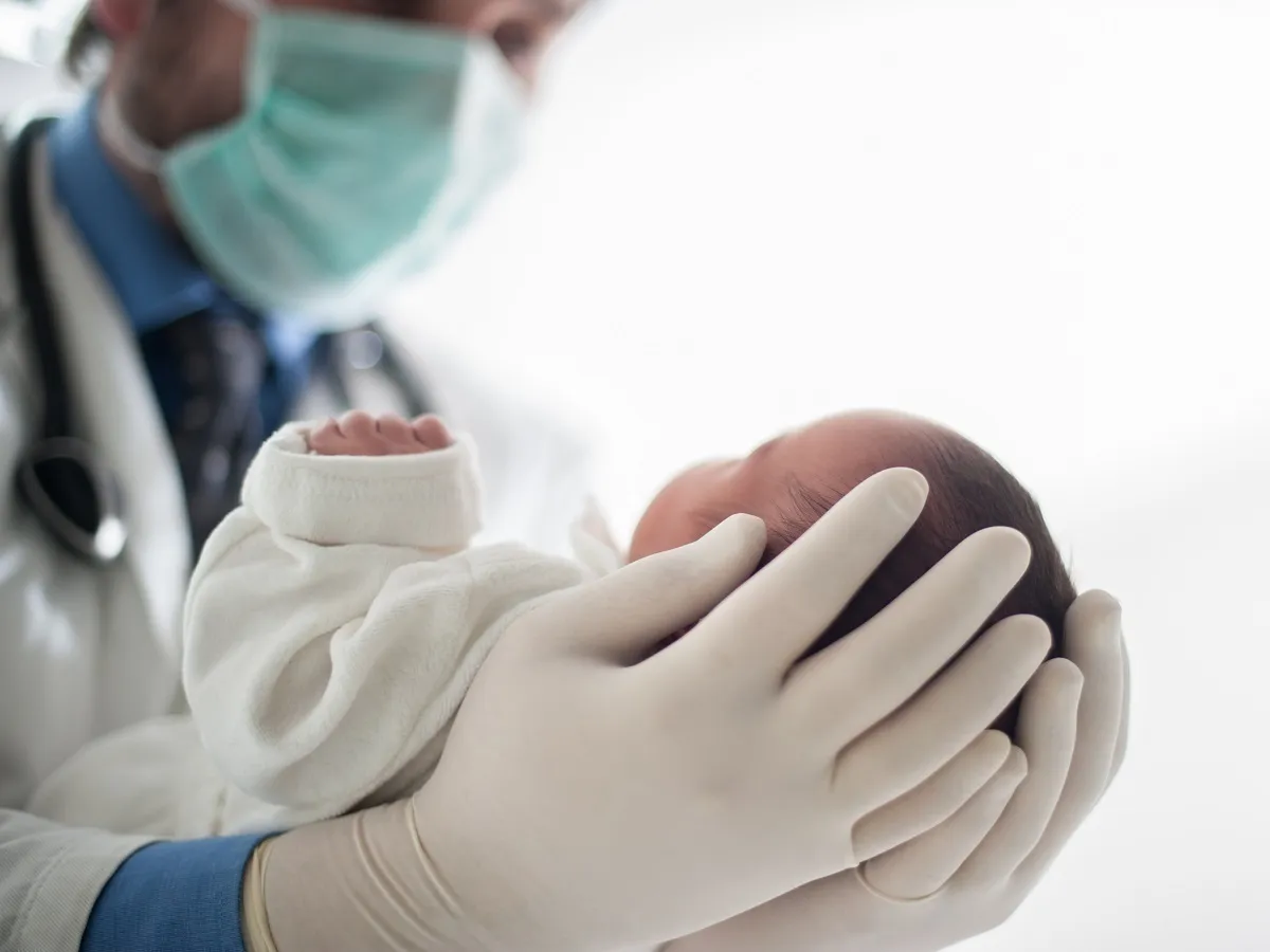 صورة لطبيب يحمل طفلاً رضيعاً