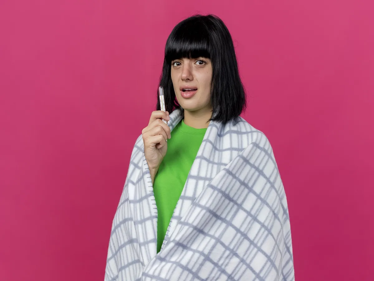 صورة لامرأة تحمل ترموميتراً لقياس الحرارة