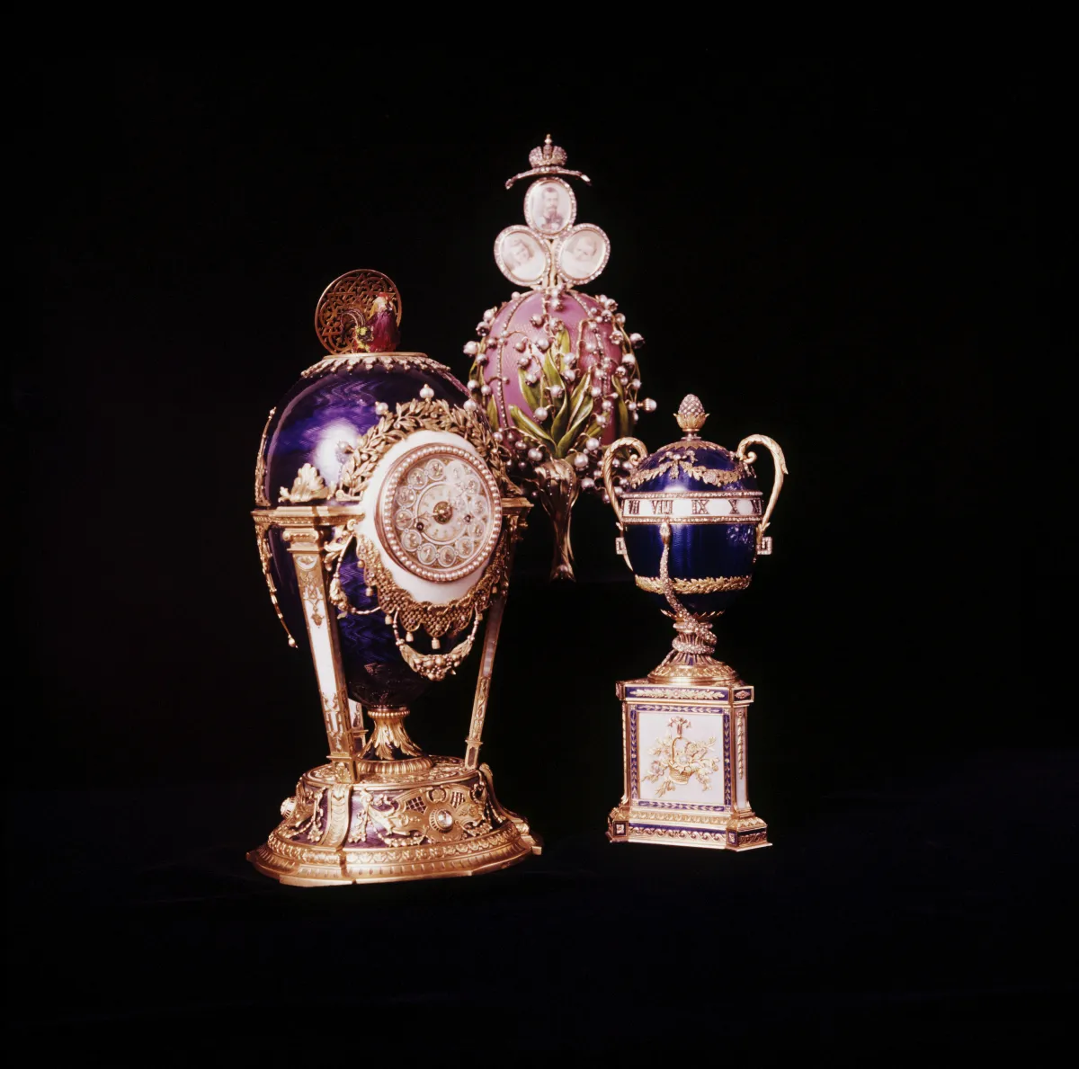 بيض فابرجيه الإمبراطوري من اليسار إلى اليمين، بيضة ساعة الوقواق وبيضة زنابق الوادي وبيضة ساعة الثعبان الأزرق، وتعلو بيضة زنابق الوادي صور القيصر وابنتيه الكبيرتين أولغا وتاتيانا (مصدر الصورة  Photo by Tony Evans/Getty Images)