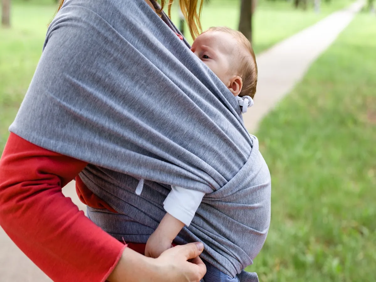 صورة لأم تحمل طفلها في شيالة الأطفال