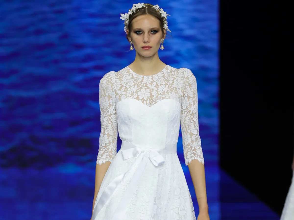 فستان أبيض من الغيبور ويتسم بحزام من الساتان الأبيض 