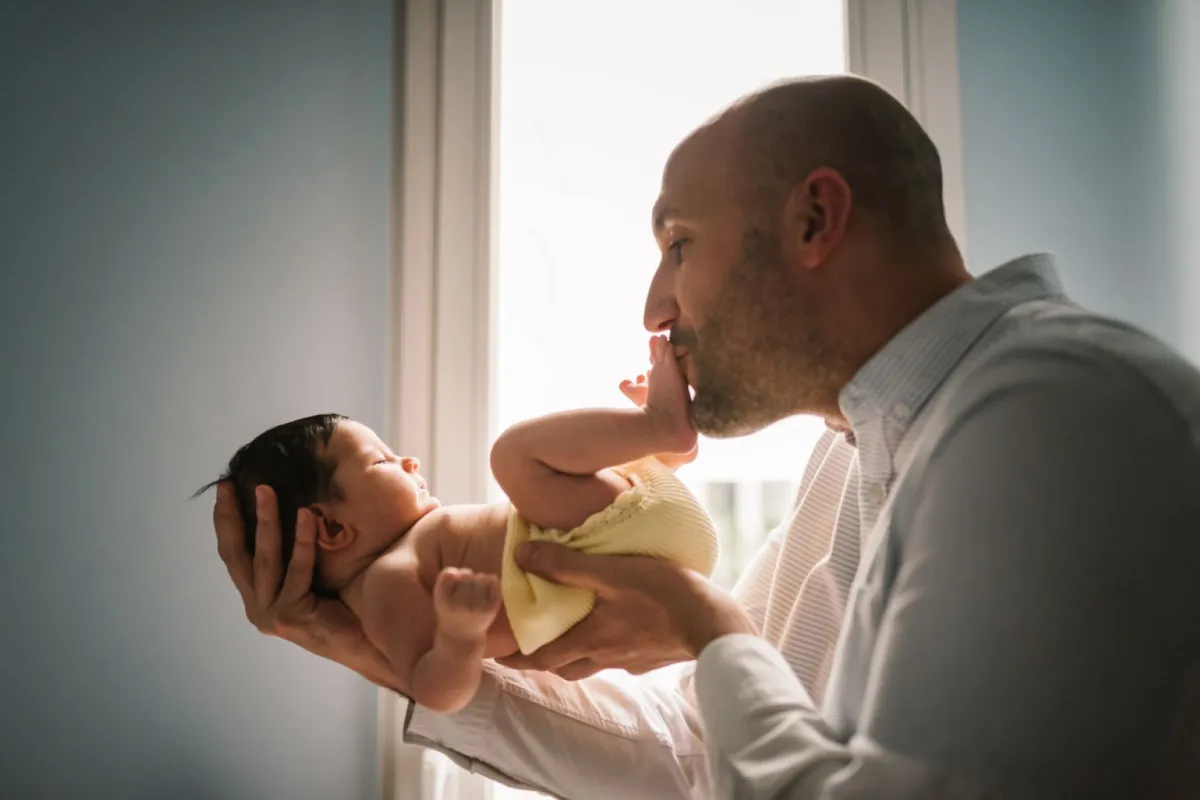 صورة أب يقبل رجلي طفله