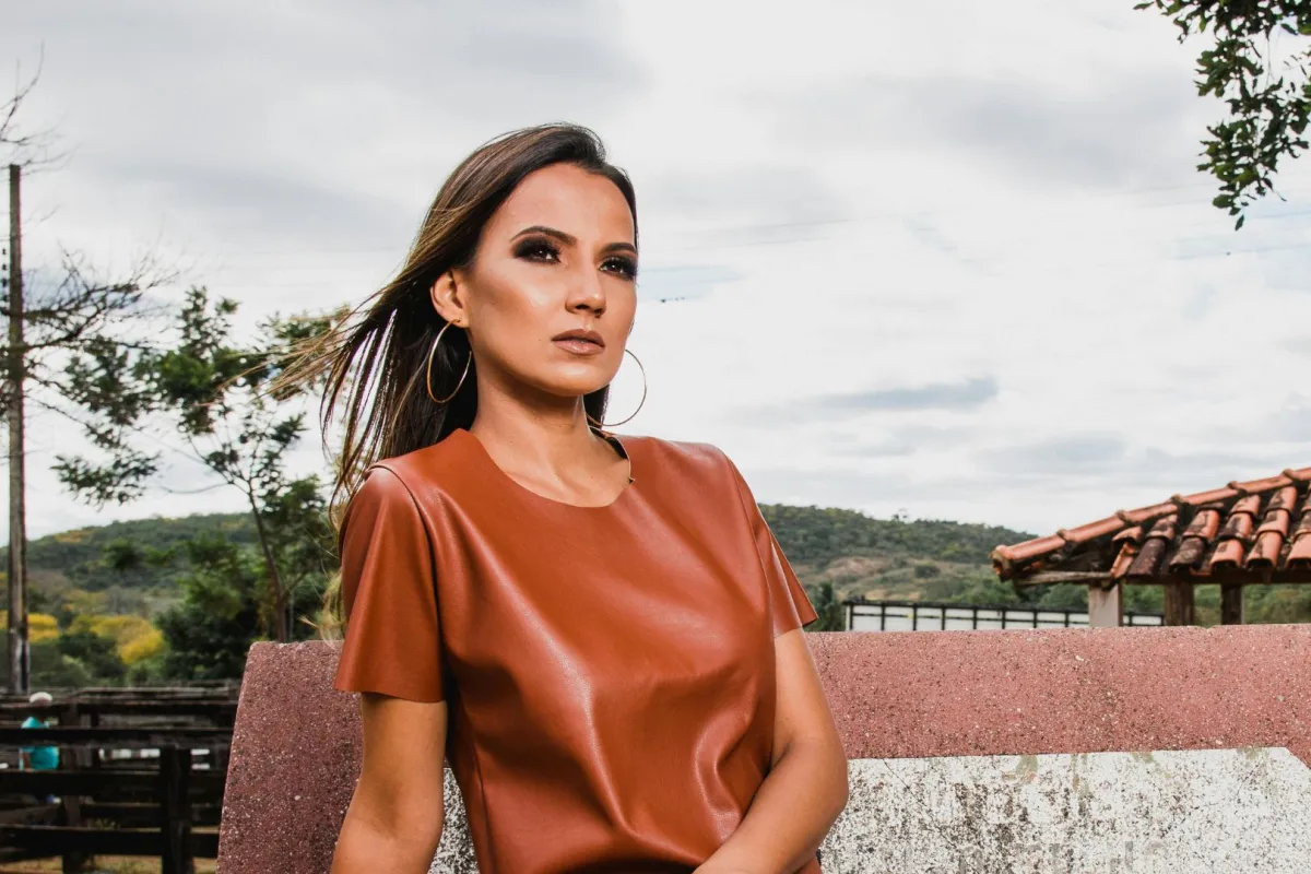 سيدة تبدو واثقة من نفسها تجلس على أريكة ومن ورائها الطبيعة الخلابة